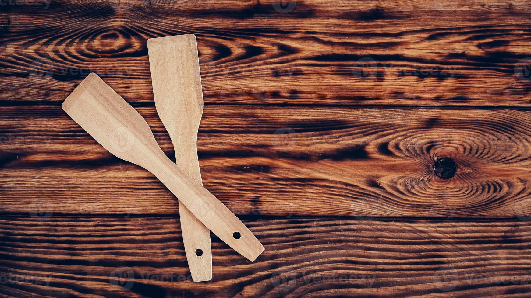 Wooden kitchen spatulas on brown table background photo