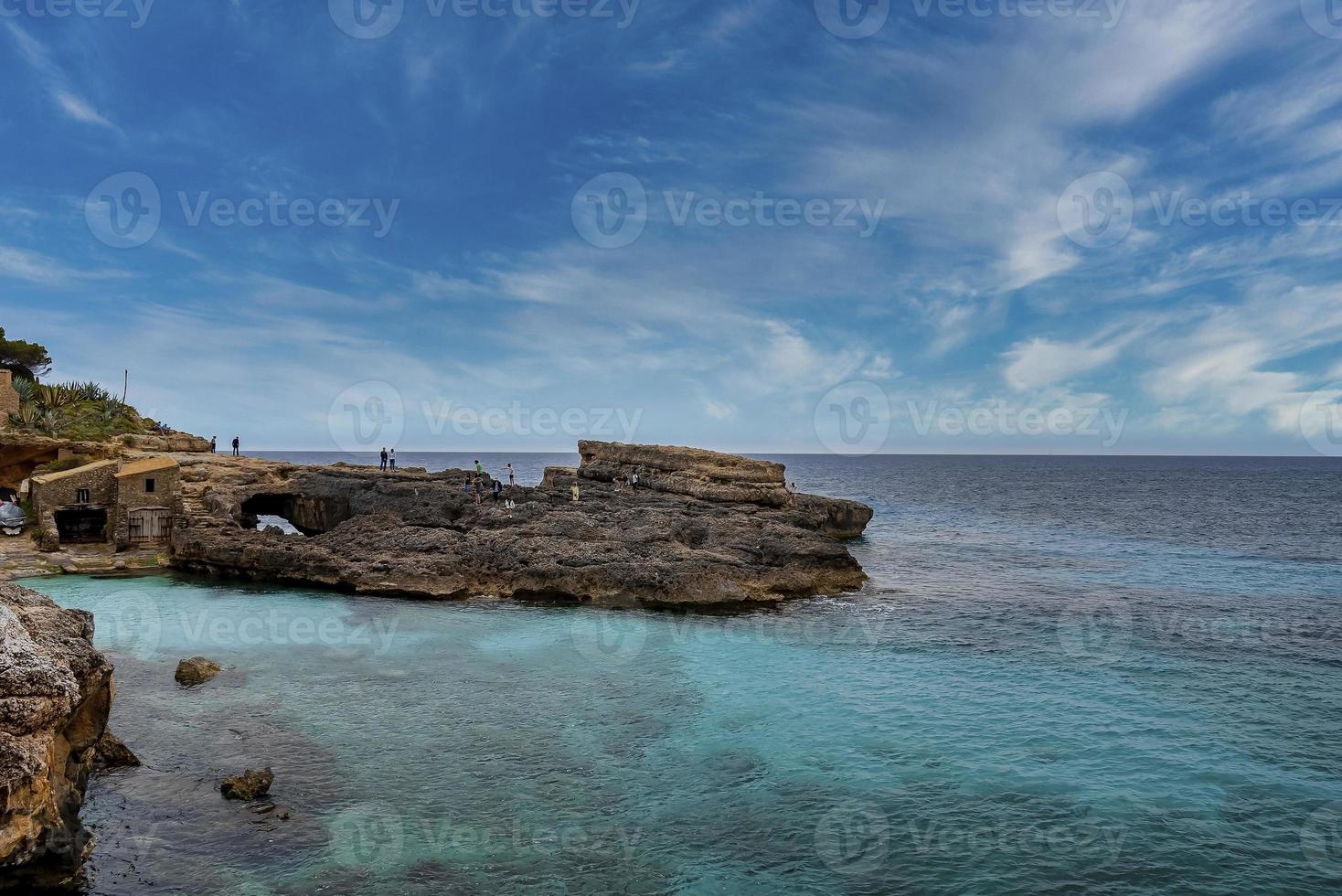 vista de los turistas que exploran el acantilado rocoso en la pintoresca isla contra el cielo azul foto