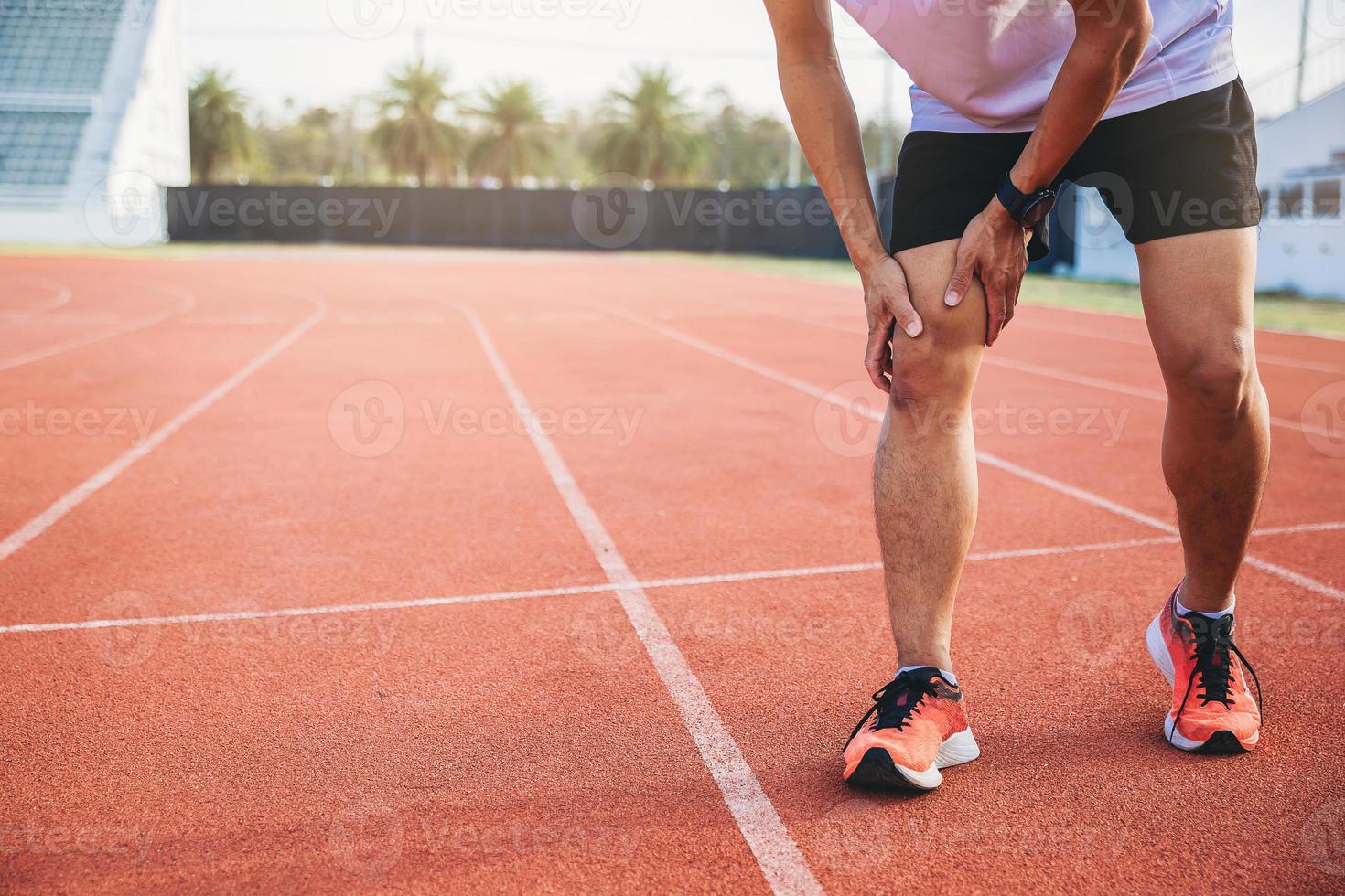 mujer corredora con lesiones deportivas en la rodilla en el hipódromo. manos sosteniendo la rodilla con un doloroso giro en la rodilla del tobillo. foto
