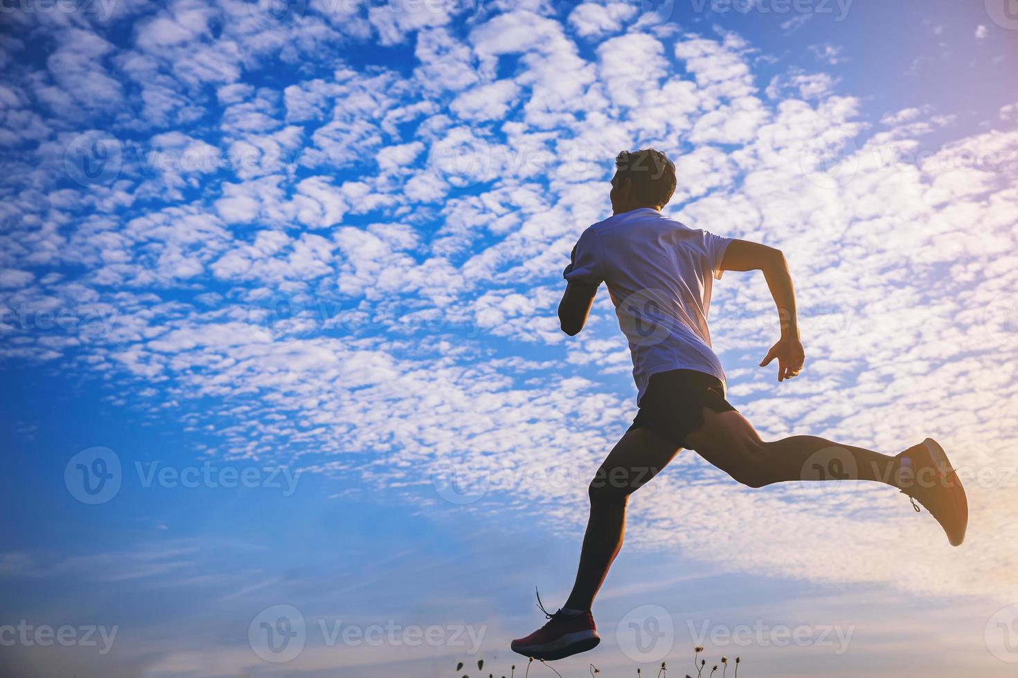 Silhouette of young man running sprinting on road. Fit runner fitness runner during outdoor workout with sunset background. photo