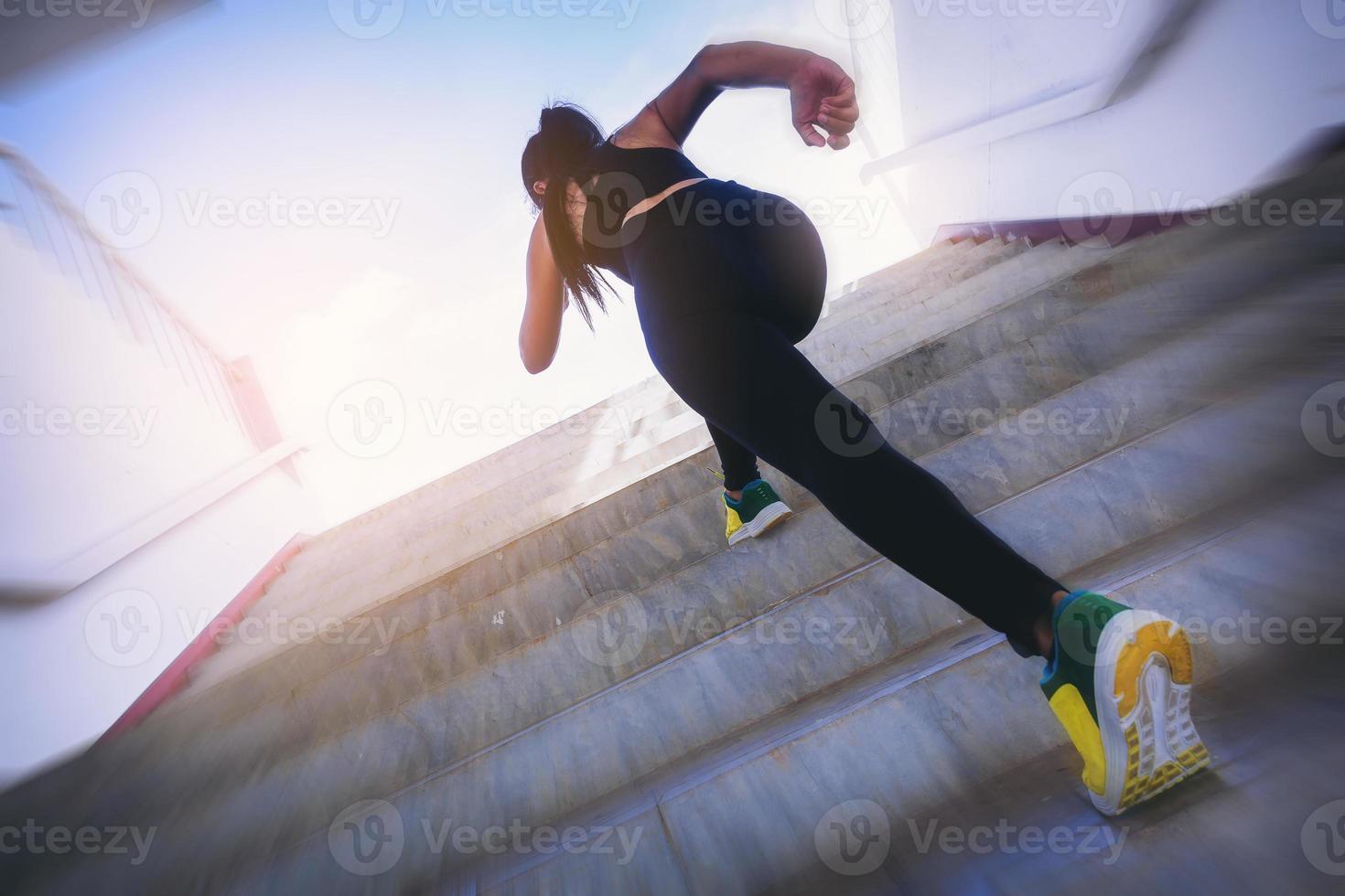 Young woman running sprinting up stairs. Fit runner fitness runner during outdoor workout. Selected focus photo