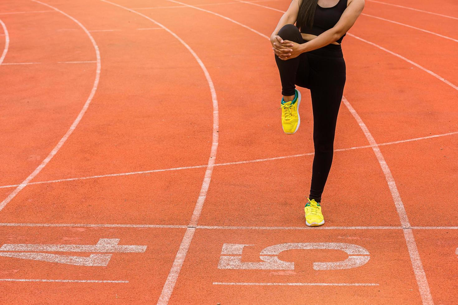 joven corredora calentándose en la pista de carreras. ajuste el entrenamiento del corredor, estire su músculo y caliéntese en la pista de carreras. foto