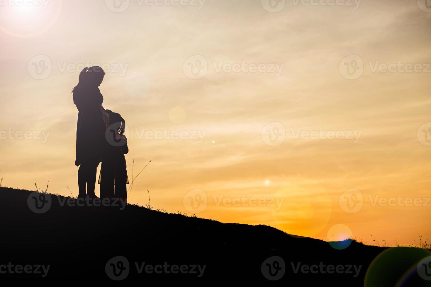 Mother encouraged her daughter out of the shadows at sunset. photo