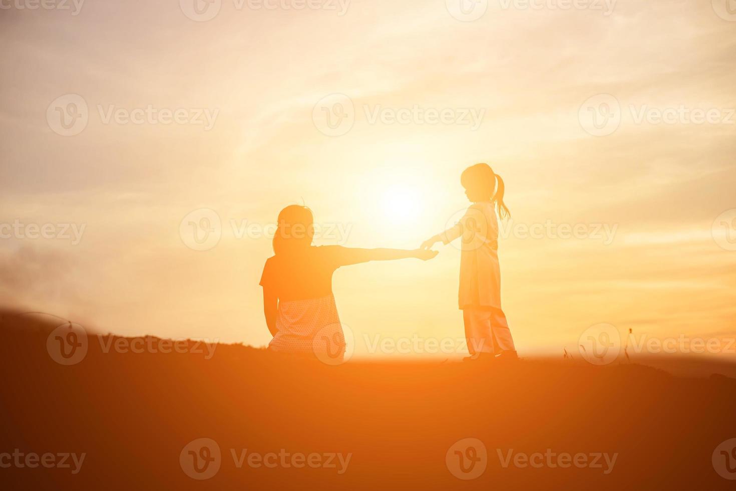 madre animó a su hija a salir de las sombras al atardecer. foto