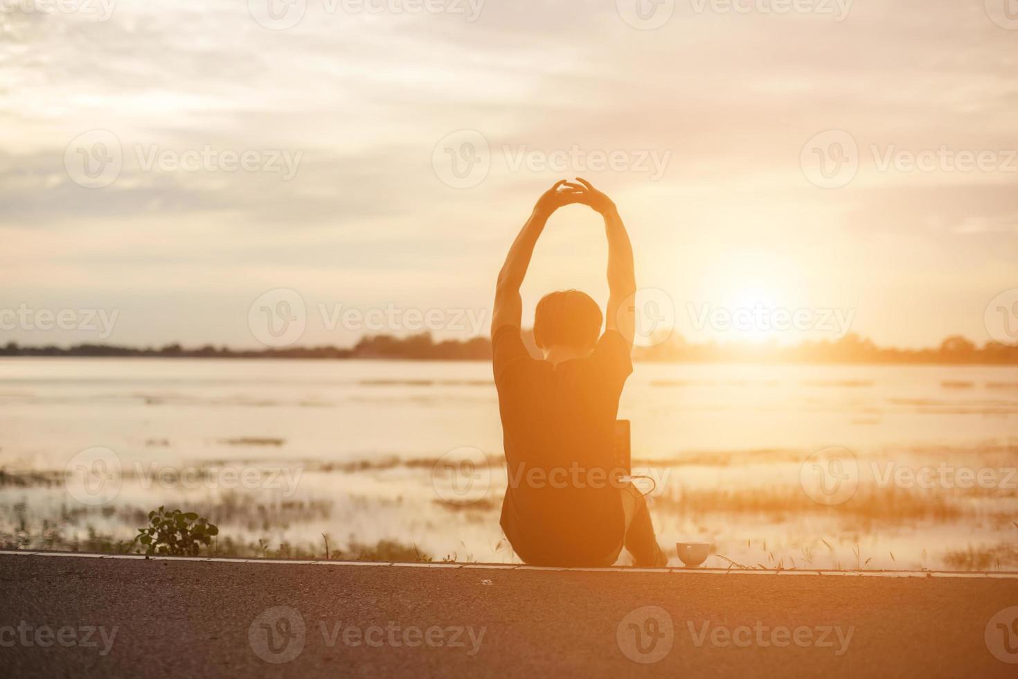 exitoso deportista levantando los brazos en el cielo dorado retroiluminación puesta de sol verano después de cruzar la carrera. atleta masculino de fitness con los brazos arriba celebrando goles después de hacer ejercicio deportivo y hacer ejercicio al aire libre. foto