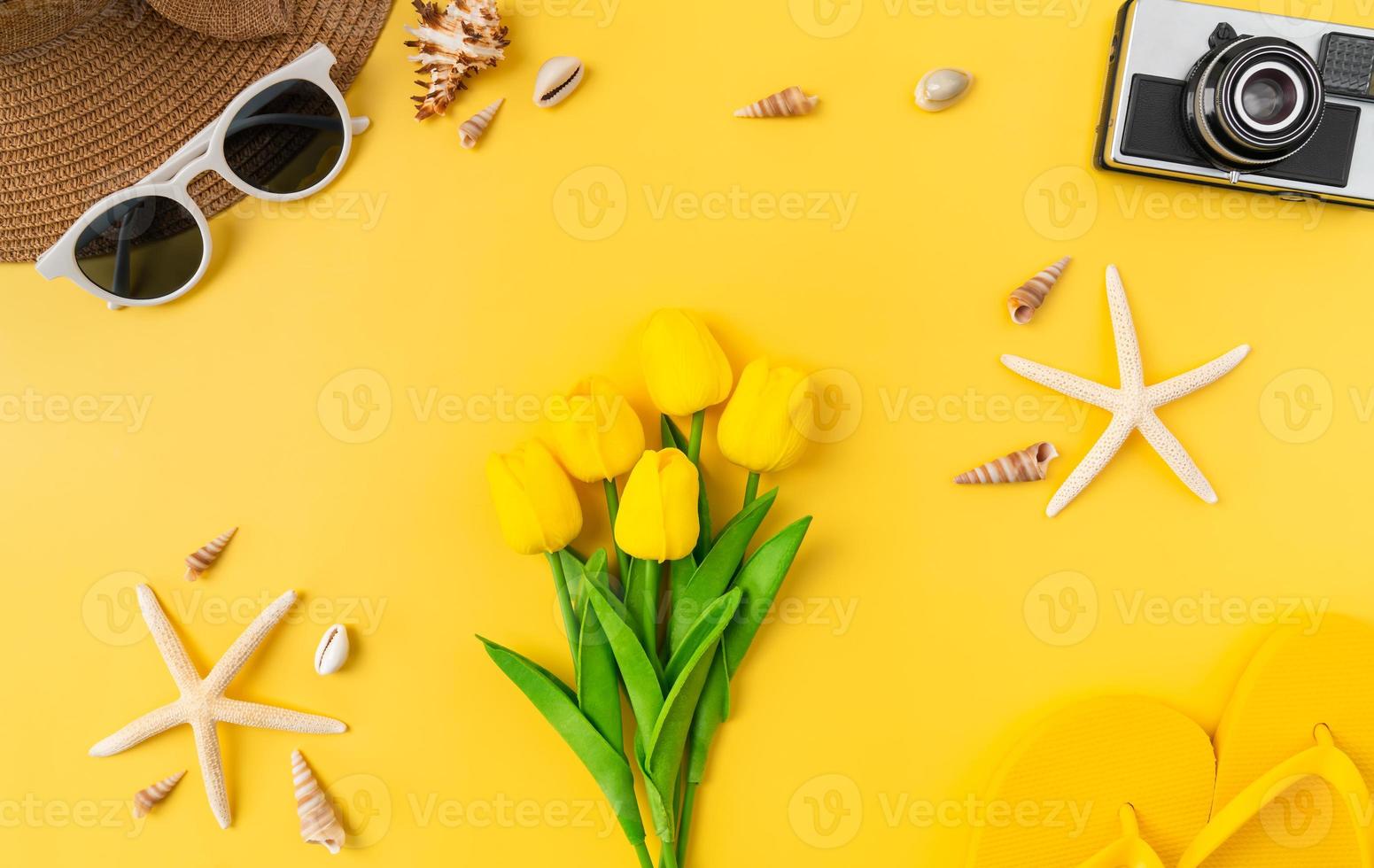 Top view of lily and flip flops, sunglasses on hat with starfish on yellow background. Summer time concept. photo