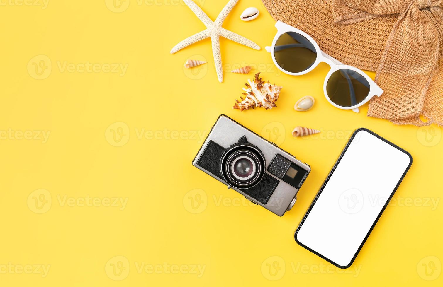 concepto de horario de verano, maqueta de teléfono inteligente de pantalla en blanco y cámara, gafas de sol con accesorios de playa en el fondo amarillo. tome su pantalla para poner publicidad. foto