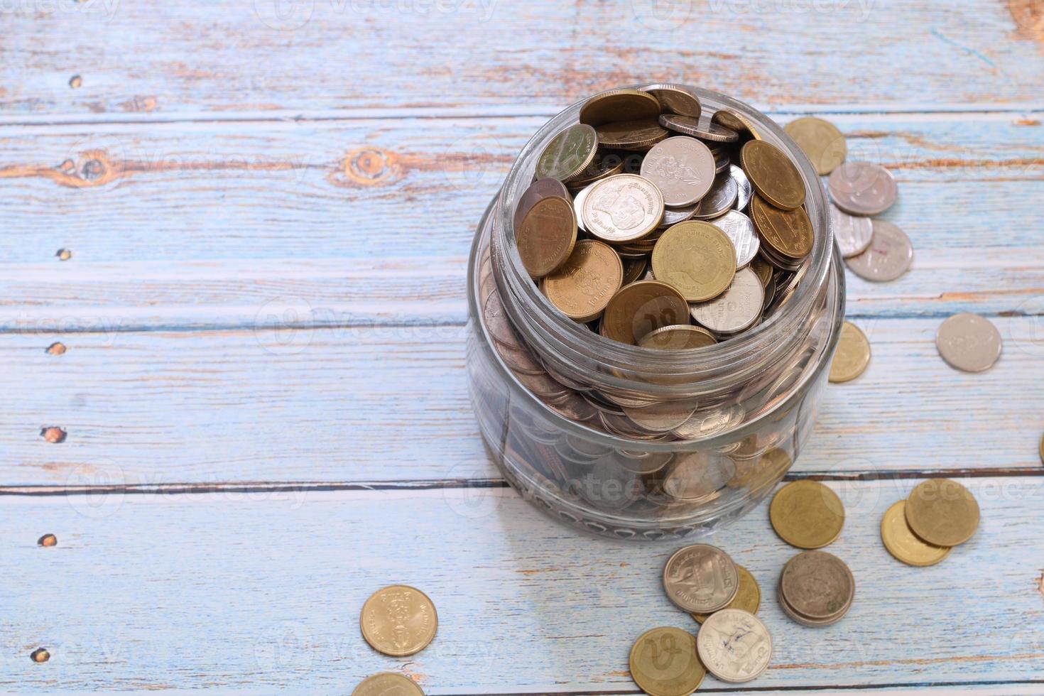 Coins in a jar or glass jar on a wooden background photo