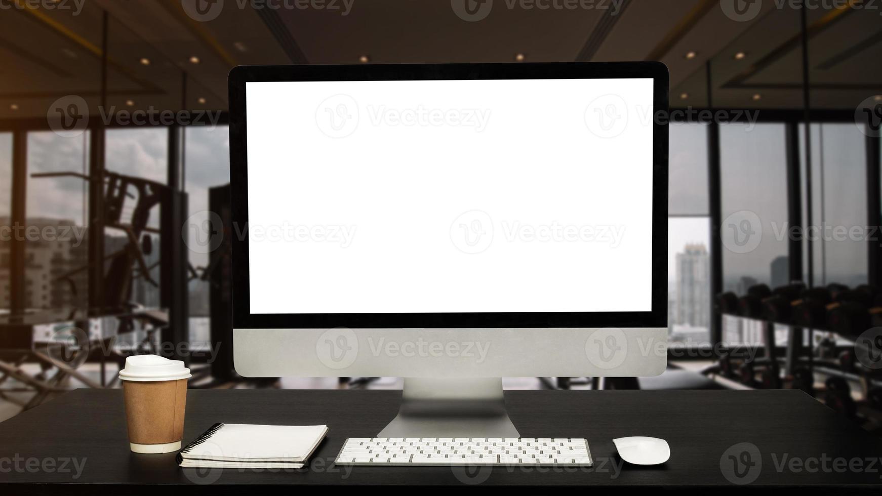 el monitor de la computadora, el teclado o la pantalla blanca aislados están en la mesa de trabajo en el gimnasio de fitness foto