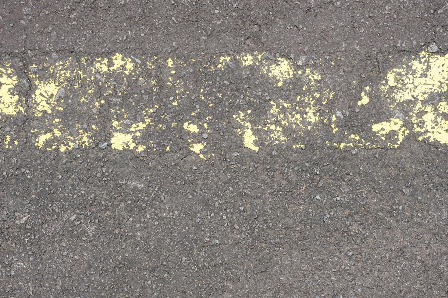 old road surface has yellow lines peeling off. photo