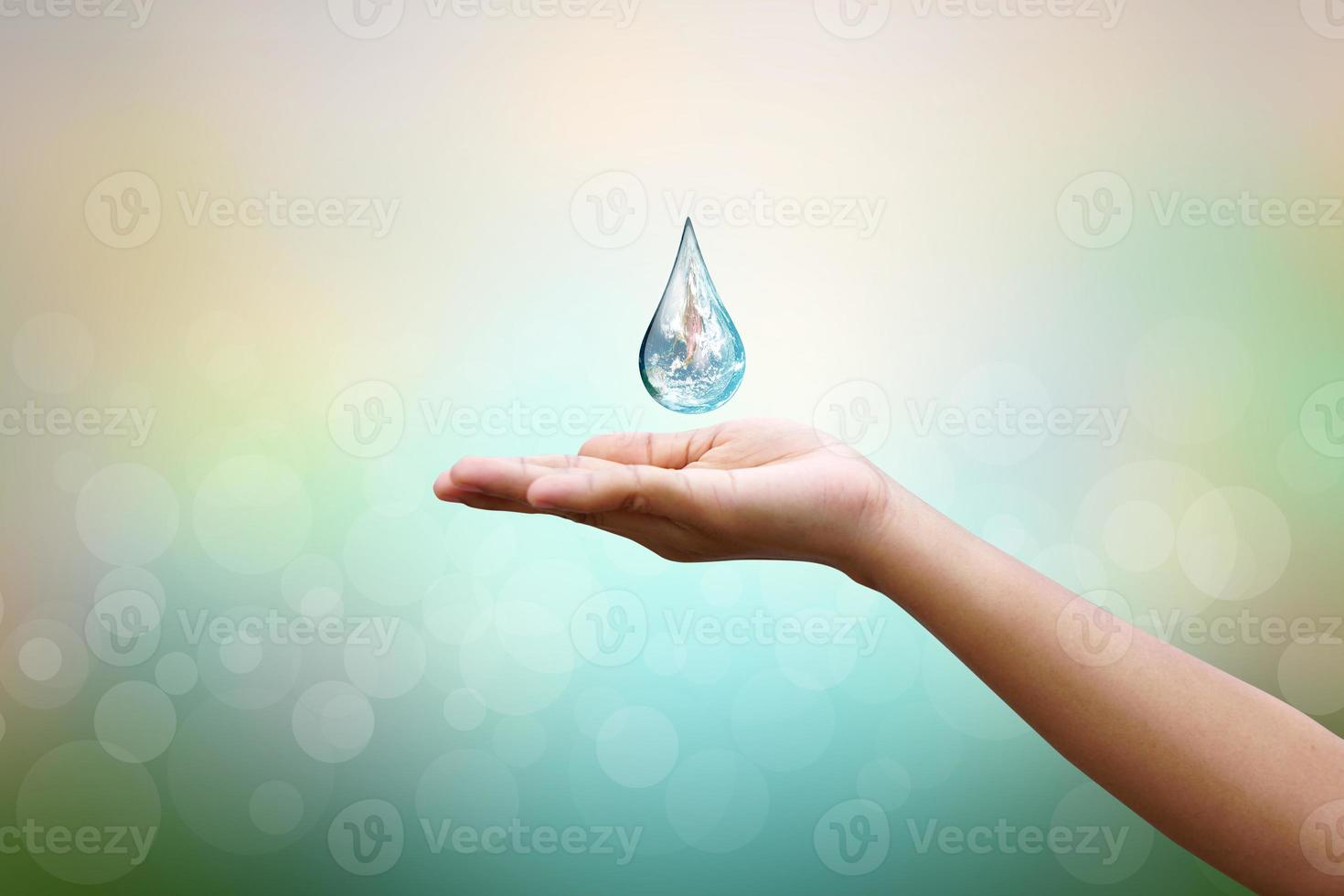 World Water Day Hands waiting for the world in water drop shape on background blurred flowers and sky with the light of the sun. Elements of this image furnished by NASA. photo