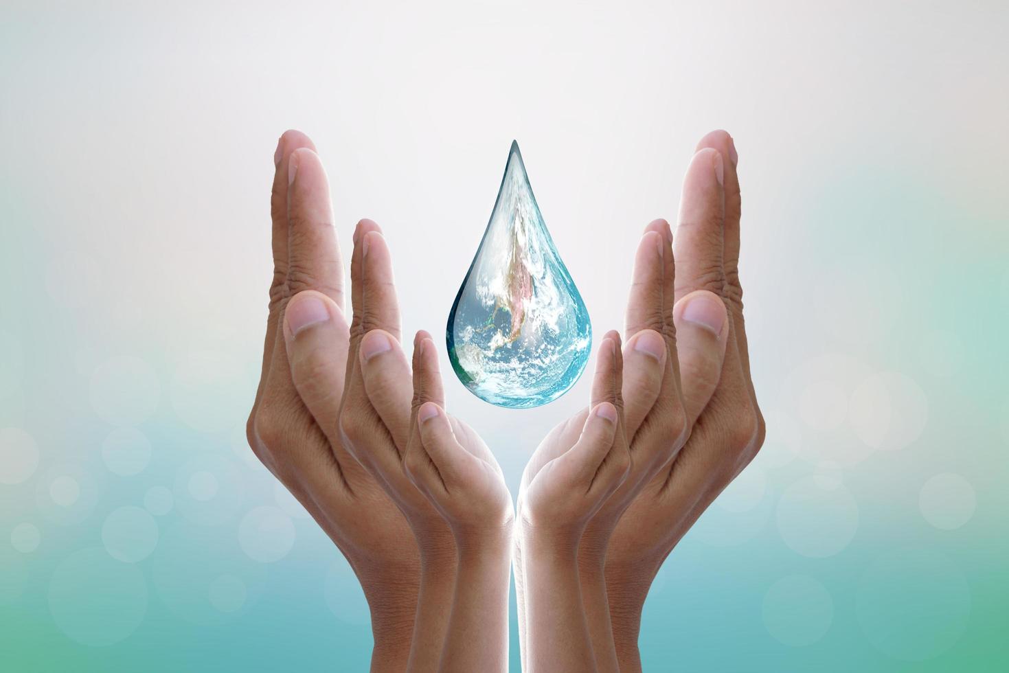 World Water Day Hands waiting for the world in water drop shape on background blurred flowers and sky with the light of the sun. Elements of this image furnished by NASA. photo