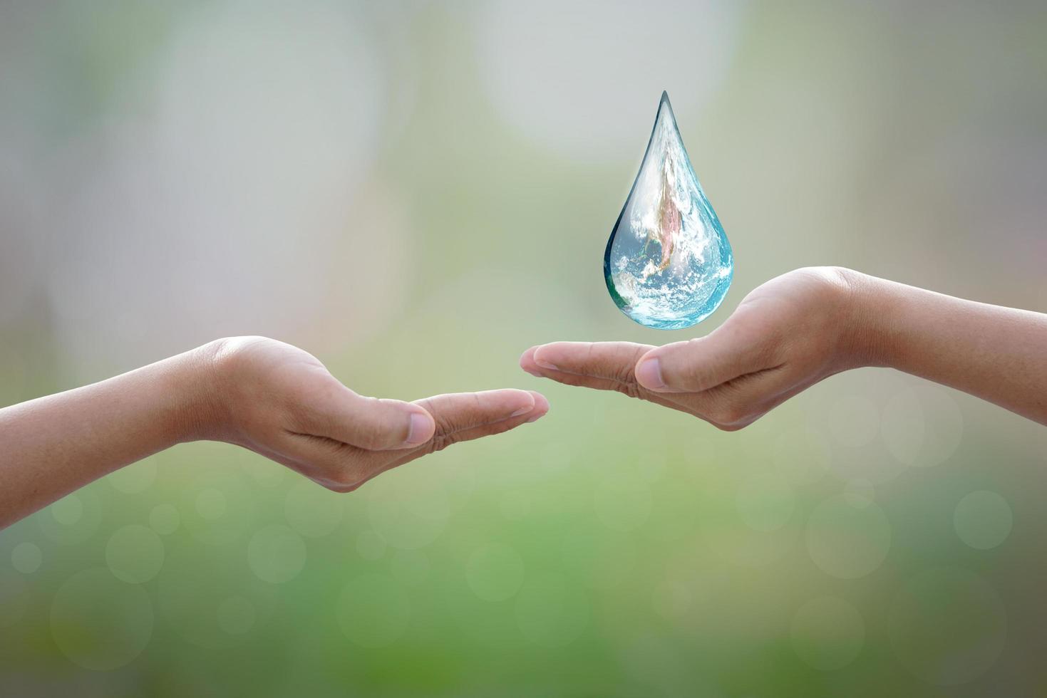 día mundial del medio ambiente. mano humana que protege la gota de agua con luz solar sobre fondo verde de la naturaleza. foto