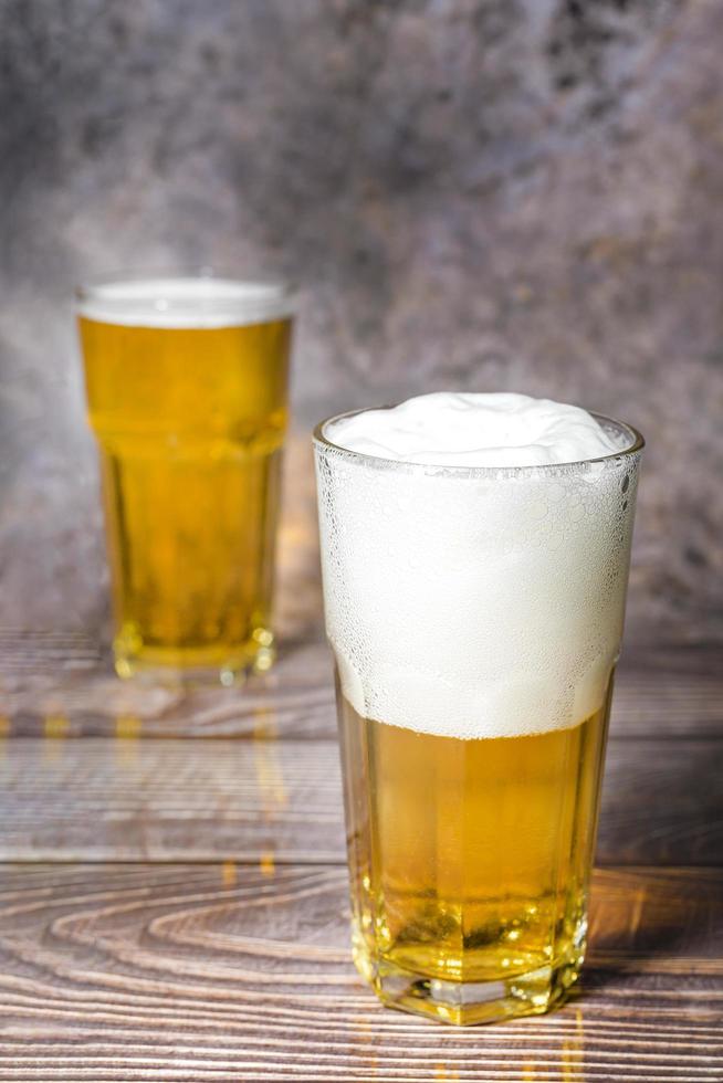 Cold craft  light Beer is pouring from bottle on wooden Table photo