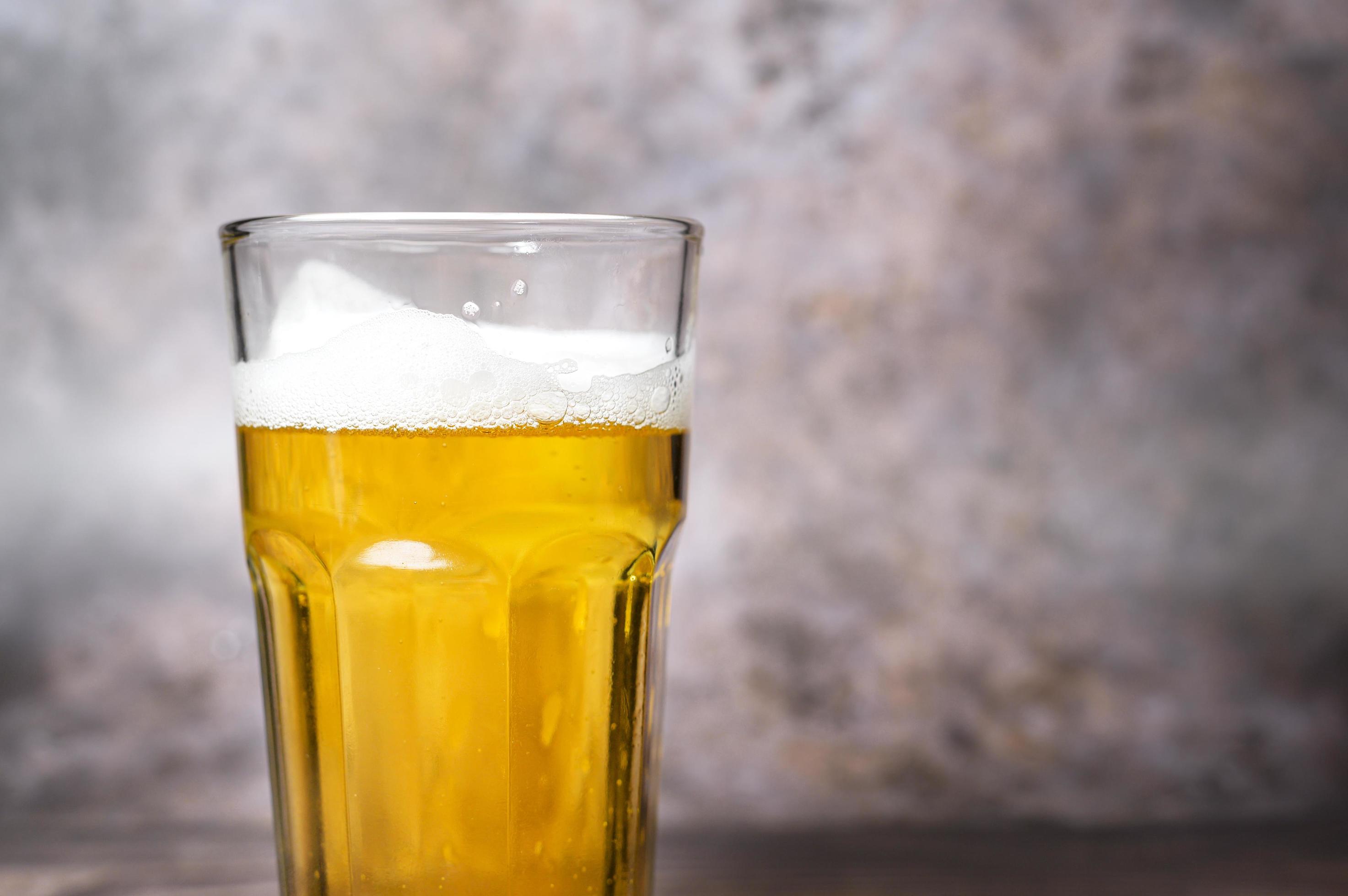 Cold craft light Beer is pouring from bottle on wooden Table 7950454