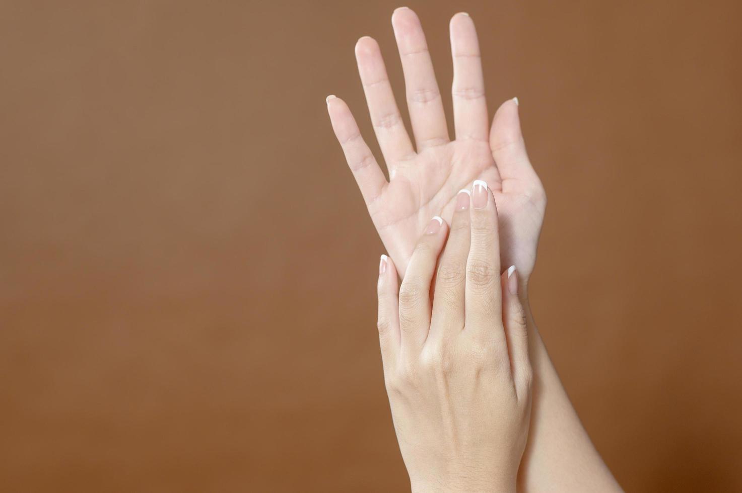 Close up young woman hand is applying cream over brown background , beauty skin care concept photo