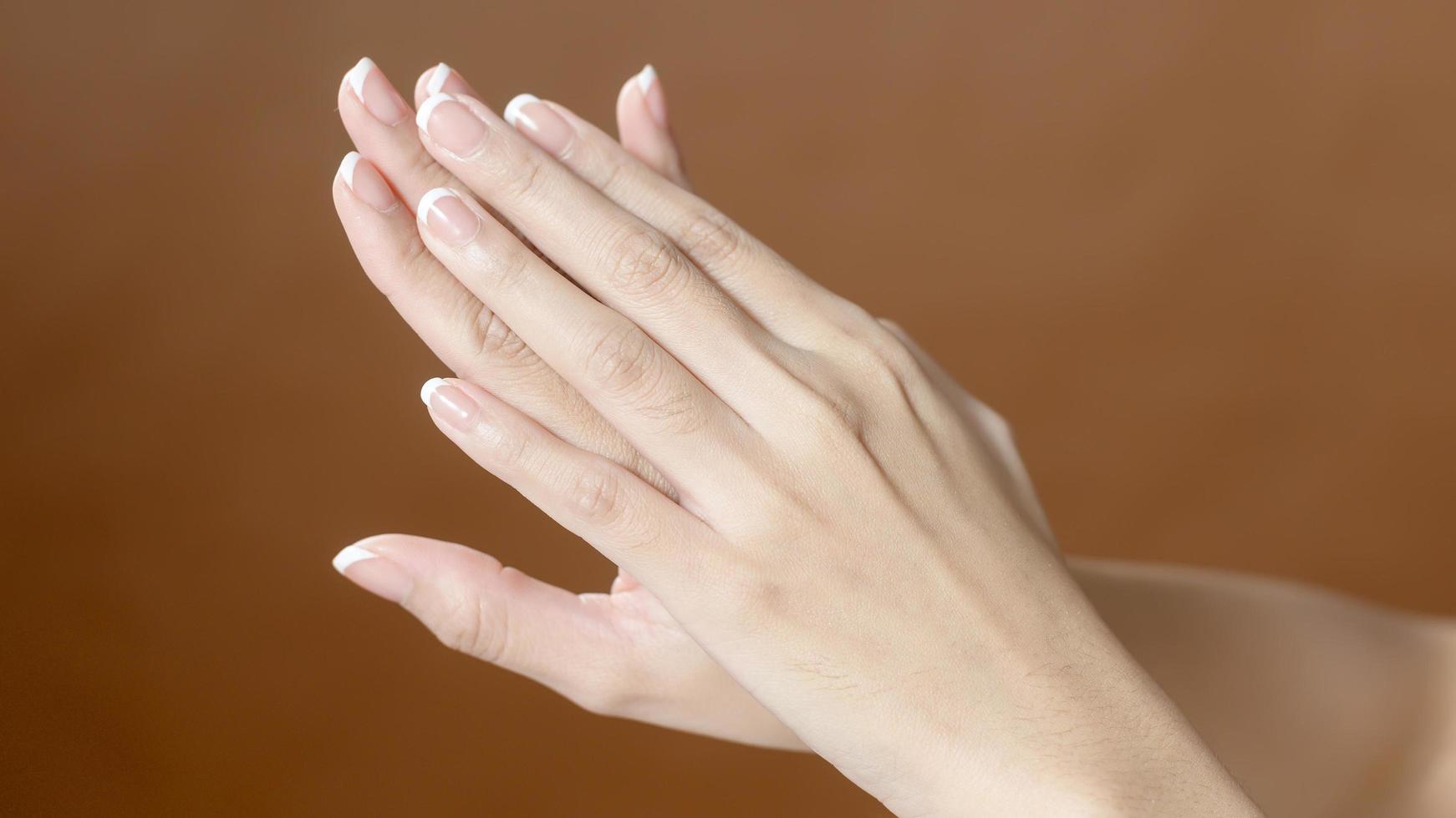 Close up young woman hand is applying cream over brown background , beauty skin care concept photo