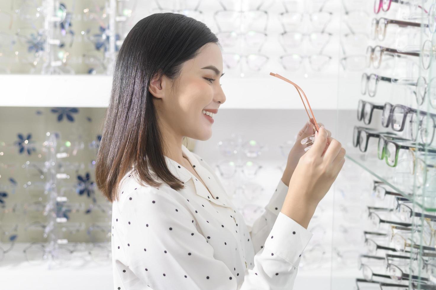 Young female customer choosing glasses in optical center, Eyecare concept. photo