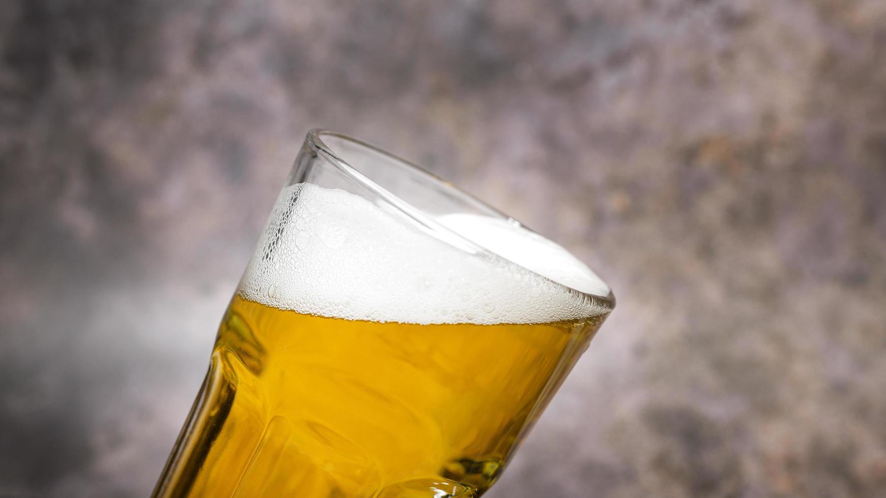 Cold craft  light Beer is pouring from bottle on wooden Table photo