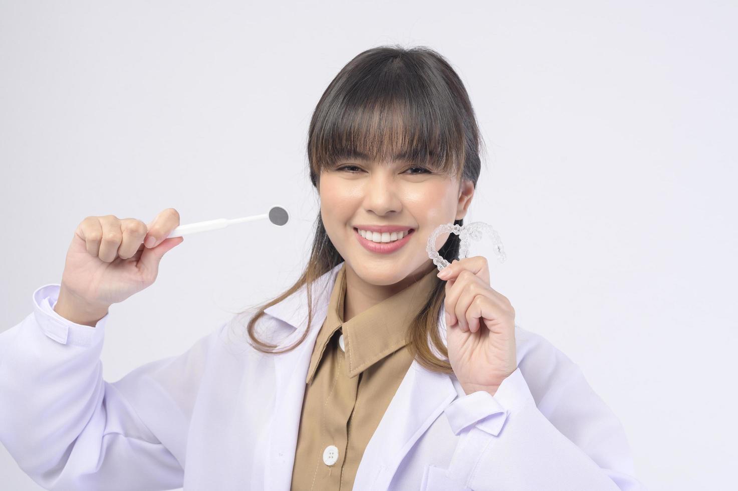 Una joven dentista sonriendo sobre un estudio de fondo blanco foto