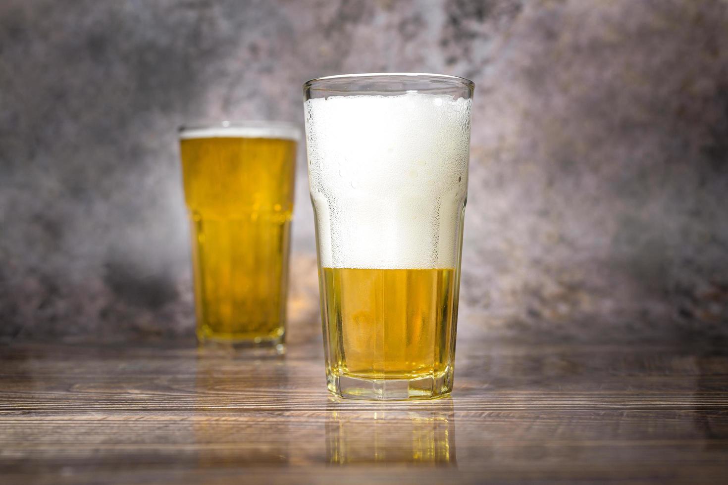 Cold craft  light Beer is pouring from bottle on wooden Table photo