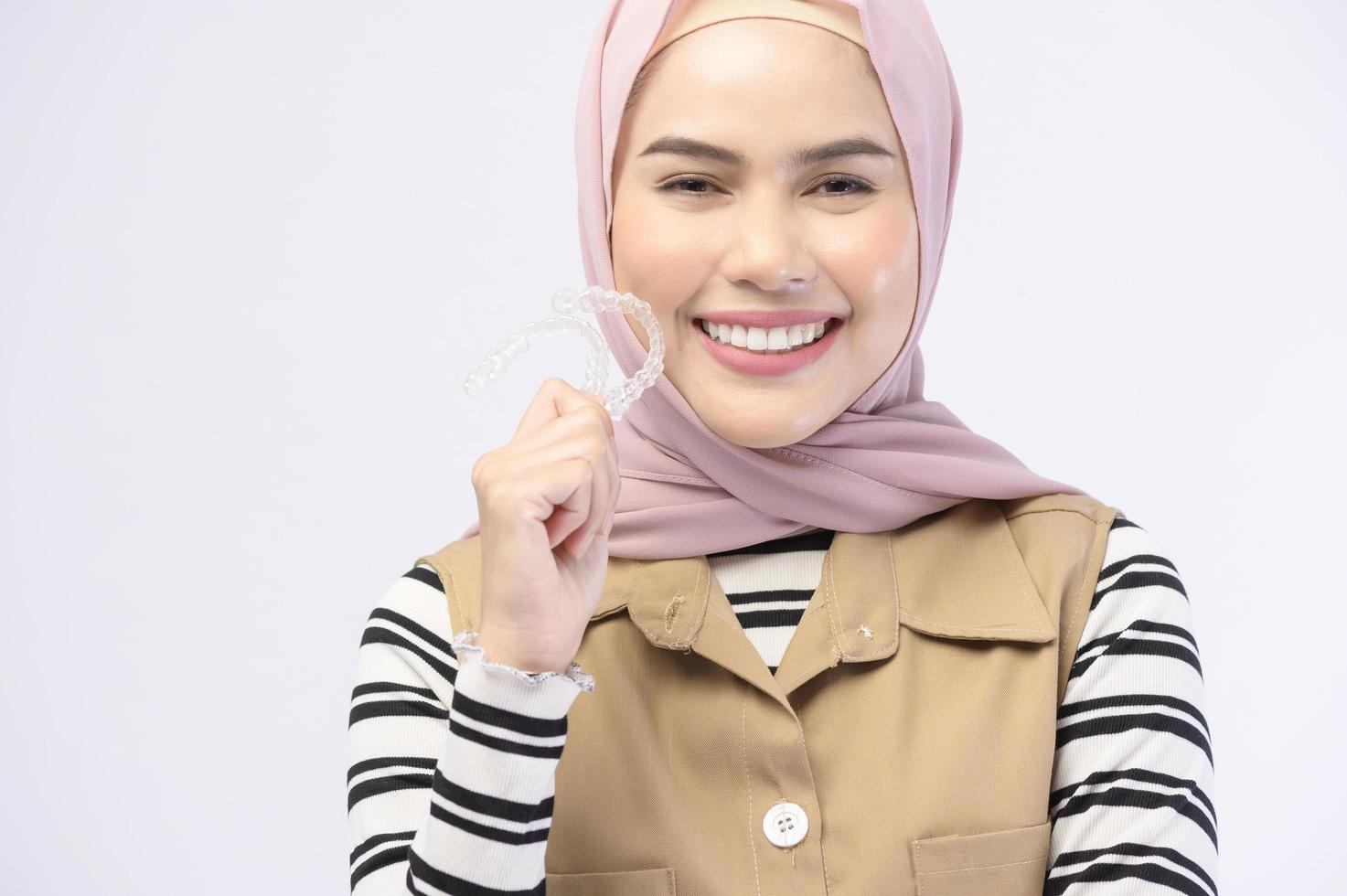 A young muslim woman holding invisalign braces in studio, dental healthcare and Orthodontic concept.. photo