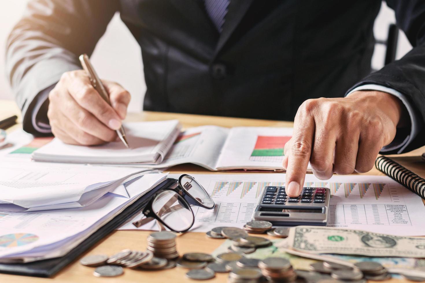 hombre de negocios que trabaja en la oficina usando una calculadora para calcular el dinero del presupuesto foto