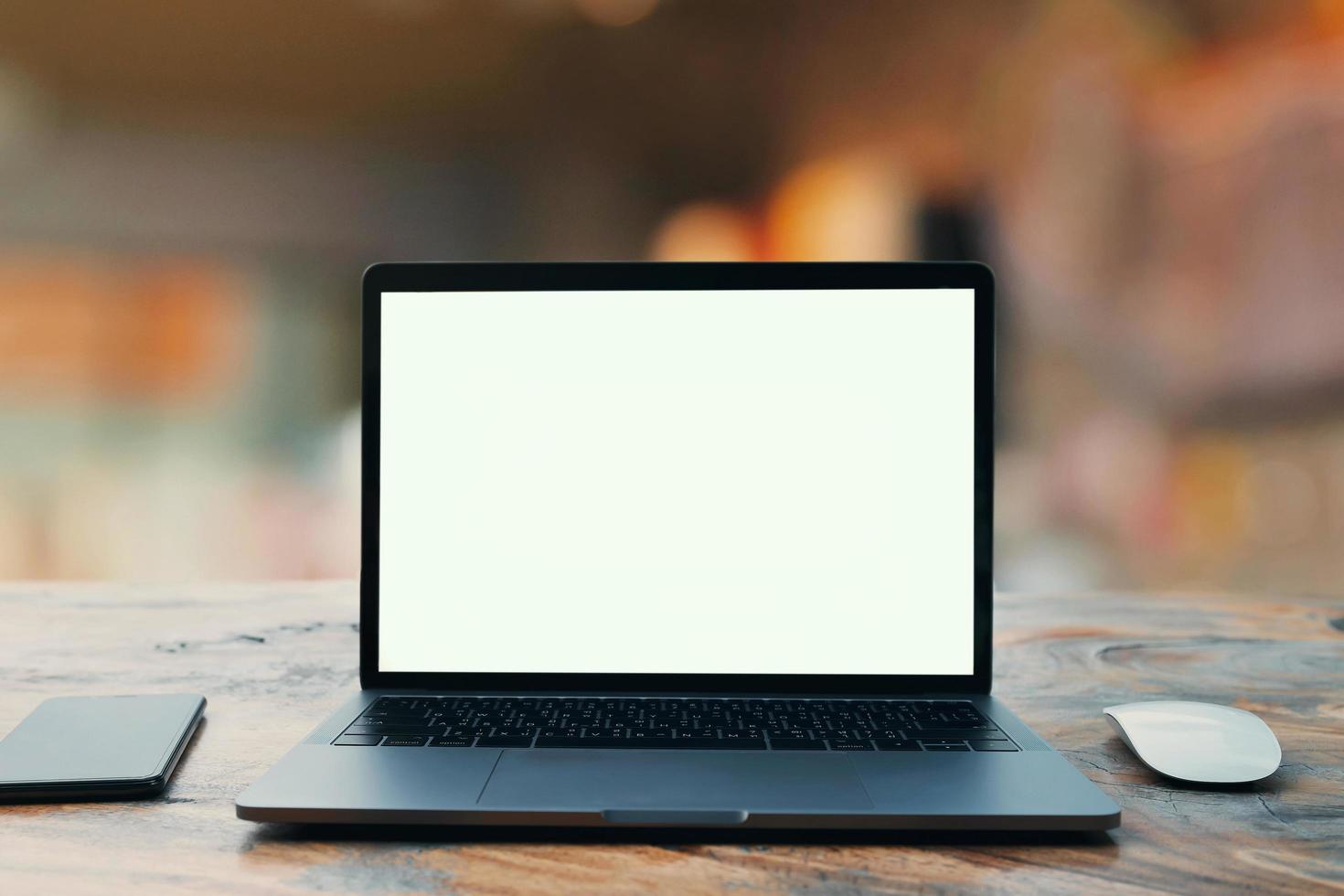 laptop computer blank white screen and mobile on table in cafe background photo