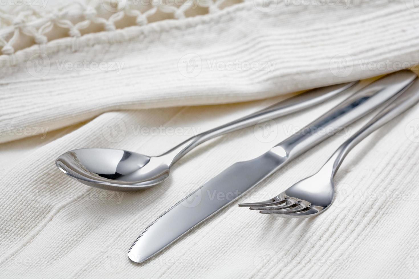 Spoon, fork and knife on white tablecloth. photo