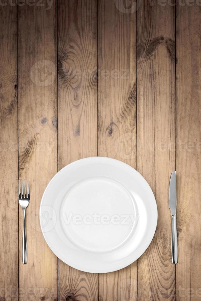 ajuste de la mesa, plato, cuchara y tenedor en la mesa de madera. foto