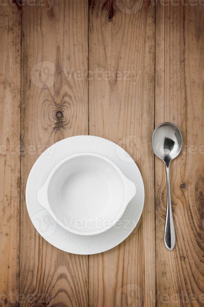 Table setting, bowl of soup and spoon on wooden table. photo