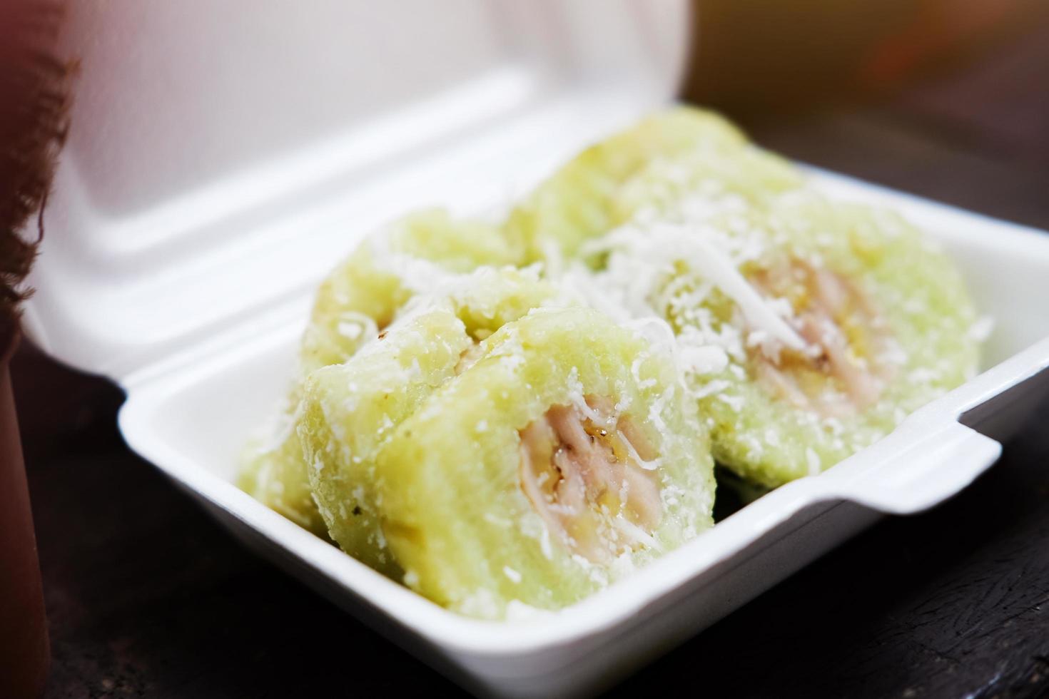 Thai sweet Dessert, Banana in steamed Sticky Rice pieces on white Foam box photo