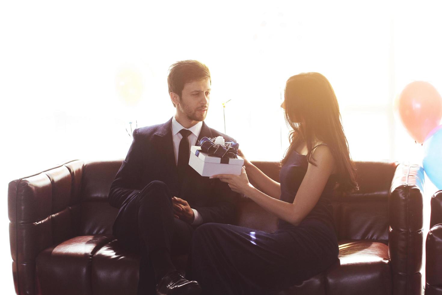 Sweet couple Love happy with surprise gift box girlfriend in christmas party, Birthday time celebration new year eve, Valentine day decoration with colorful balloon on brown sofa in living room photo