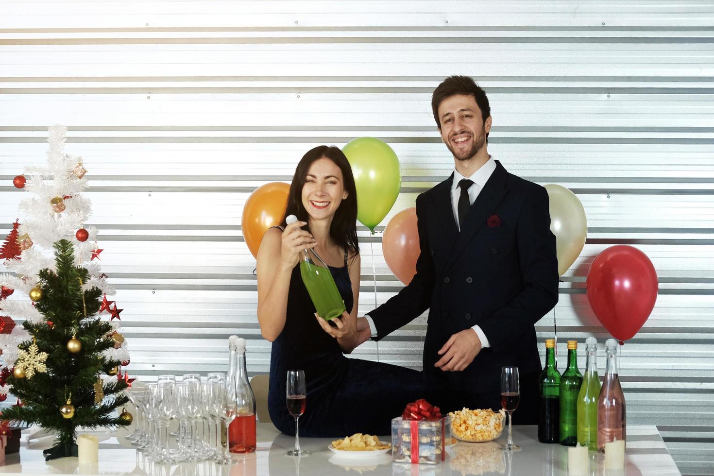 dulce pareja amor sonrisa y pasar romántico bebiendo vino en navidad y celebrando la víspera de año nuevo, día de san valentín con globos coloridos y cajas de regalo en el área de la despensa foto