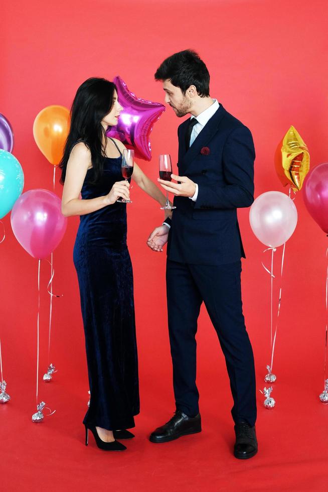 Sweet couple Love smile and spending Romantic with drinking wine in christmas time and celebrating new year eve, valentine day with colorful balloon on red background photo