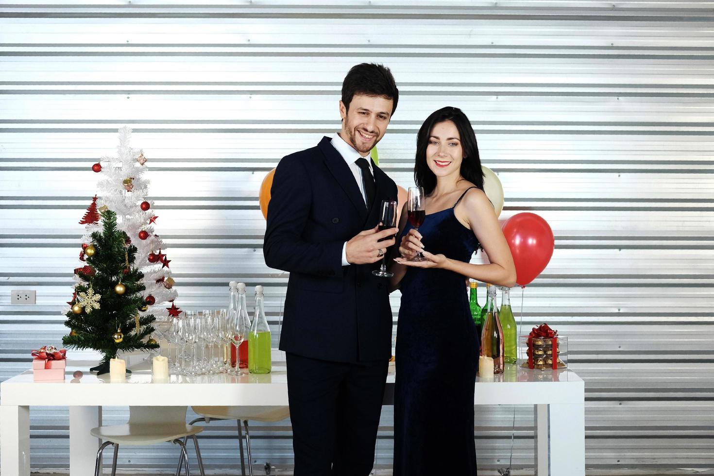 dulce pareja amor sonrisa y pasar romántico bebiendo vino en navidad y celebrando la víspera de año nuevo, día de san valentín con globos coloridos y cajas de regalo en el área de la despensa foto