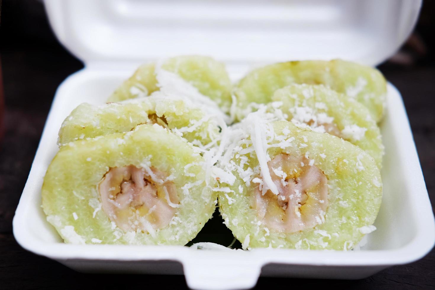 Thai sweet Dessert, Banana in steamed Sticky Rice pieces on white Foam box photo