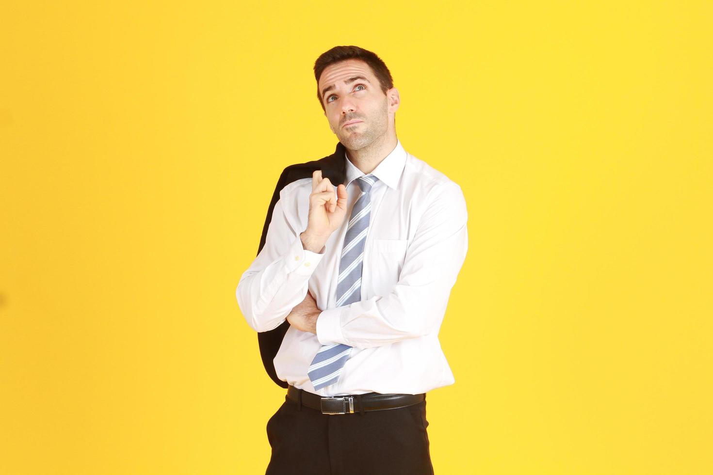 apuesto e inteligente hombre de negocios con traje y camisa blanca relajándose en isolatred sobre fondo amarillo. copie el espacio foto