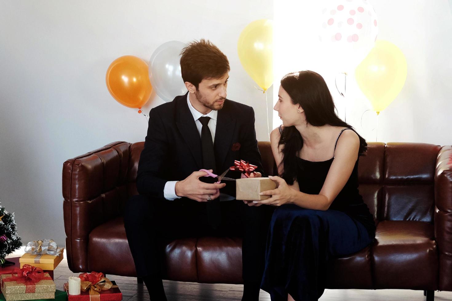 Sweet couple Love smile and spending Romantic christmas time and celebrating new year eve on Brown Sofa decoration with Christmas tree, colorful balloon and Gift Boxes in Living room at home photo