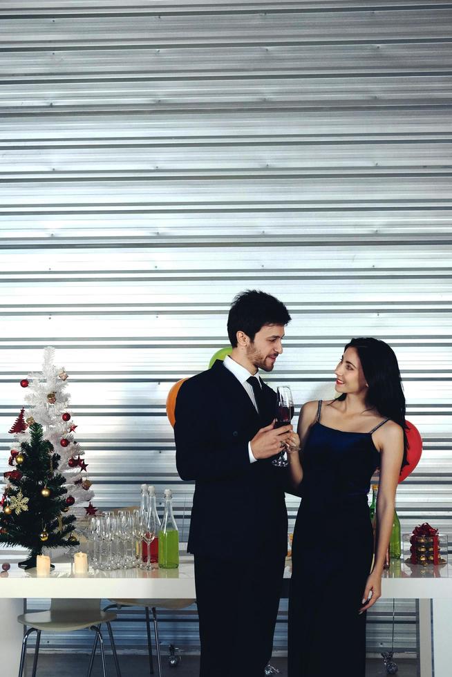 dulce pareja amor sonrisa y pasar romántico bebiendo vino en navidad y celebrando la víspera de año nuevo, día de san valentín con globos coloridos y cajas de regalo en el área de la despensa foto
