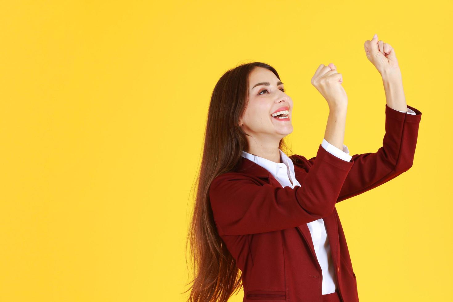 una exitosa mujer de negocios sonrió y levantó la mano por el éxito en trabajos aislados de fondo amarillo foto