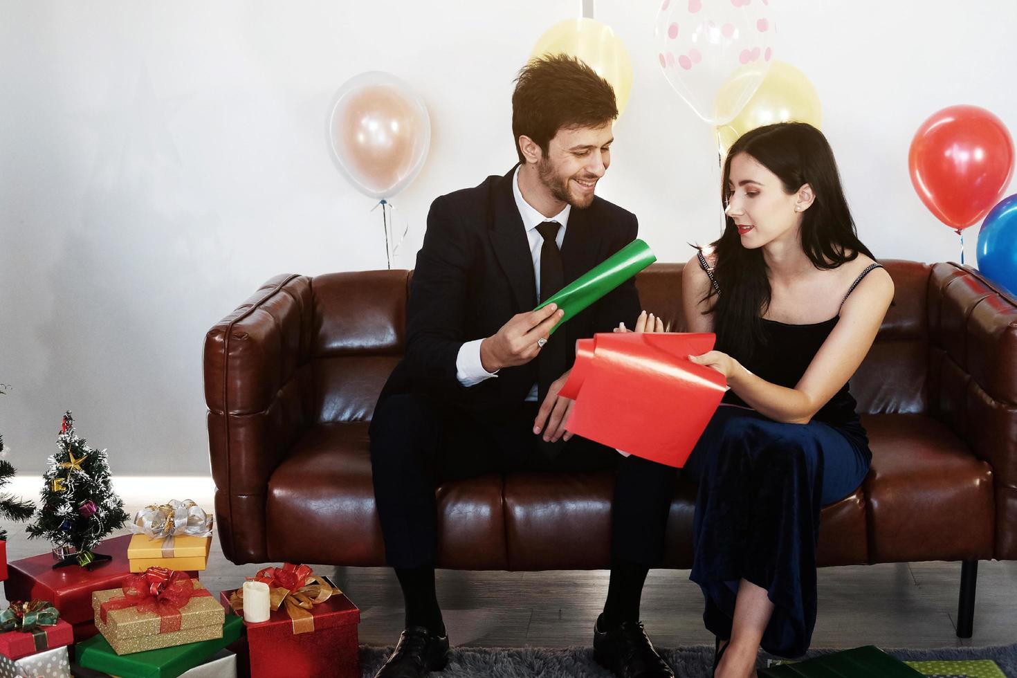 Sweet couple Love smile and spending Romantic christmas time and celebrating new year eve on Brown Sofa decoration with Christmas tree, colorful balloon and Gift Boxes in Living room at home photo