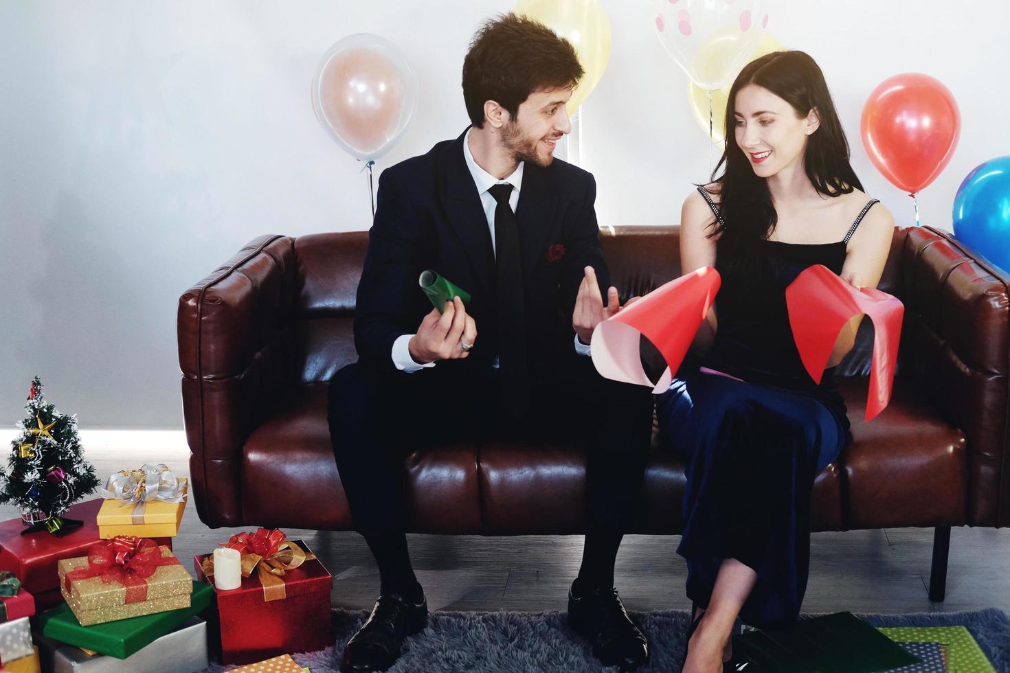 Sweet couple Love smile and spending Romantic christmas time and celebrating new year eve on Brown Sofa decoration with Christmas tree, colorful balloon and Gift Boxes in Living room at home photo