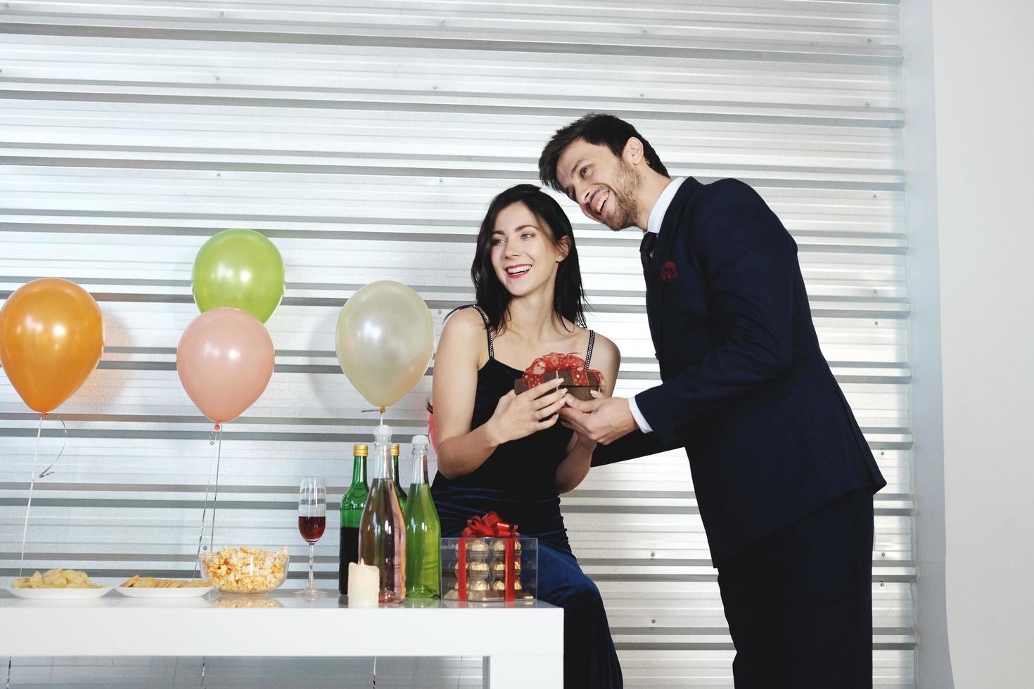 dulce pareja amor feliz con caja de regalo sorpresa novia en navidad y celebrando la víspera de año nuevo, decoración del día de san valentín con árbol de navidad, globo colorido y cajas de regalo en el área de la despensa foto