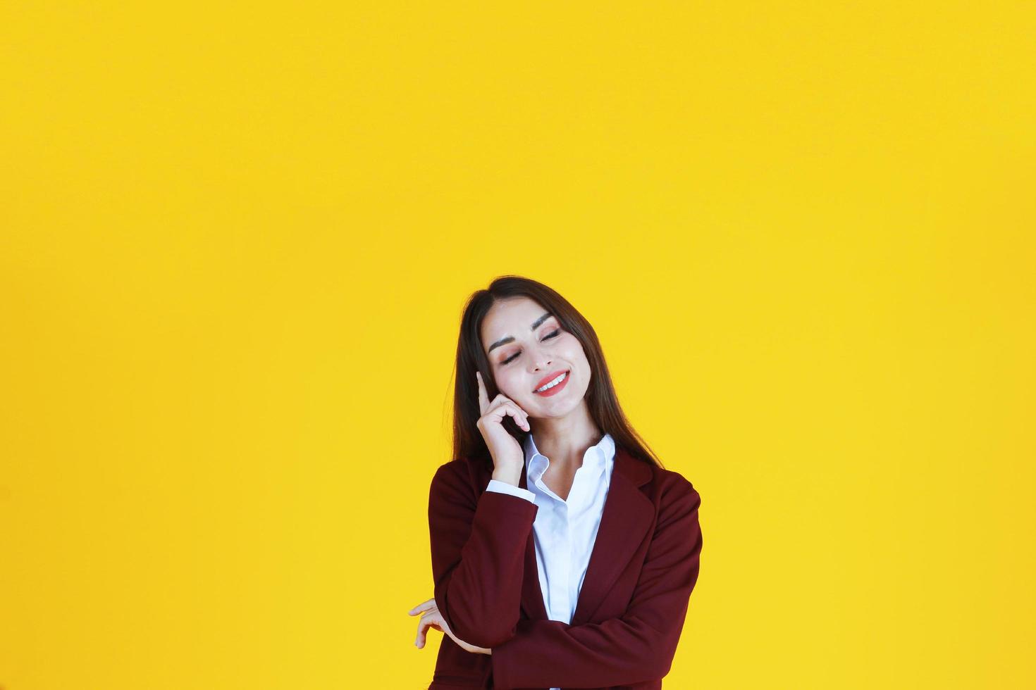 Business Caucasian woman in red suit smiling and thinking for good idea isolated on yellow background. photo