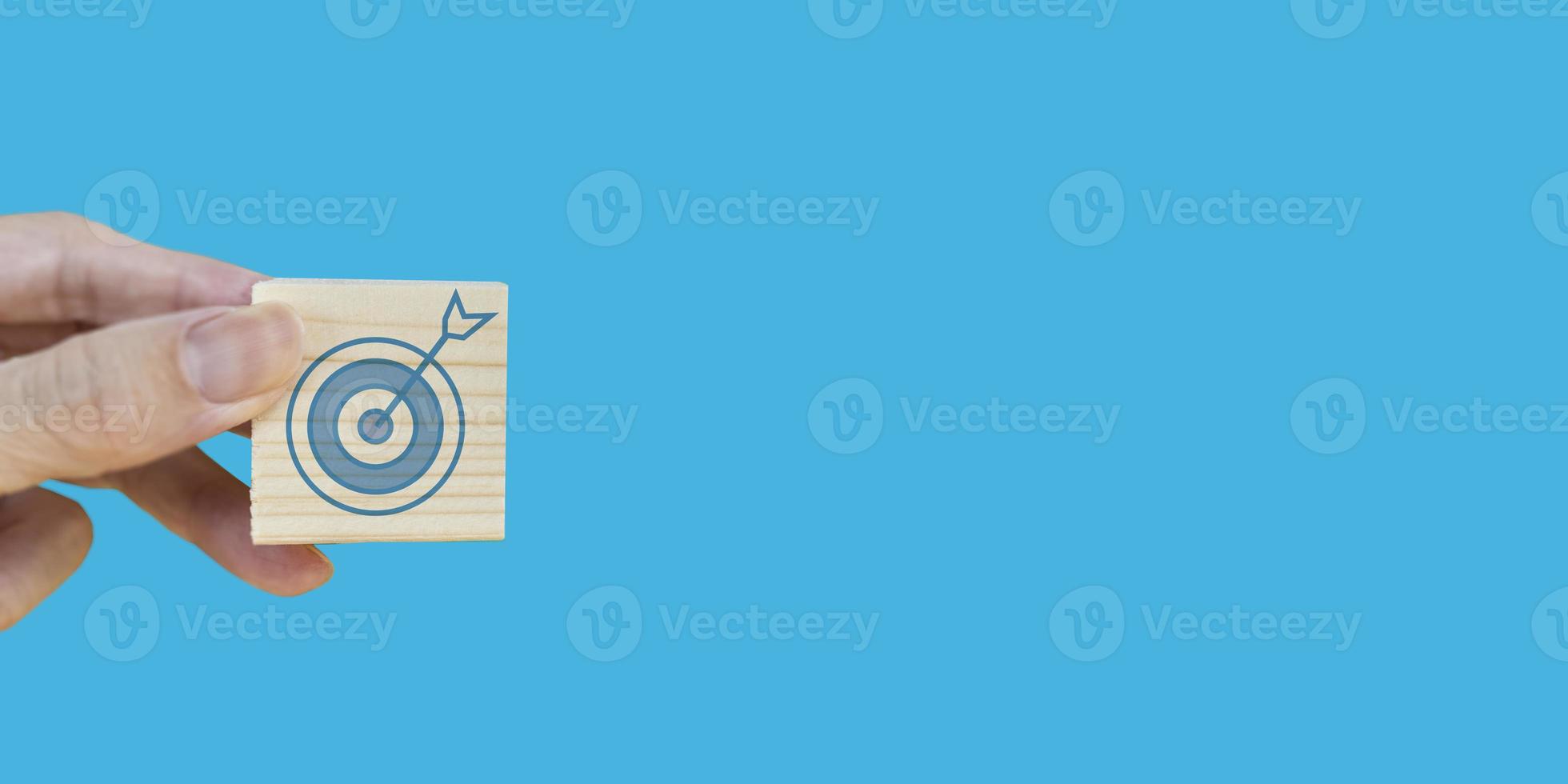 A businessman holds a wooden box with a target icon in his hand.,Getting to the goals of doing business photo