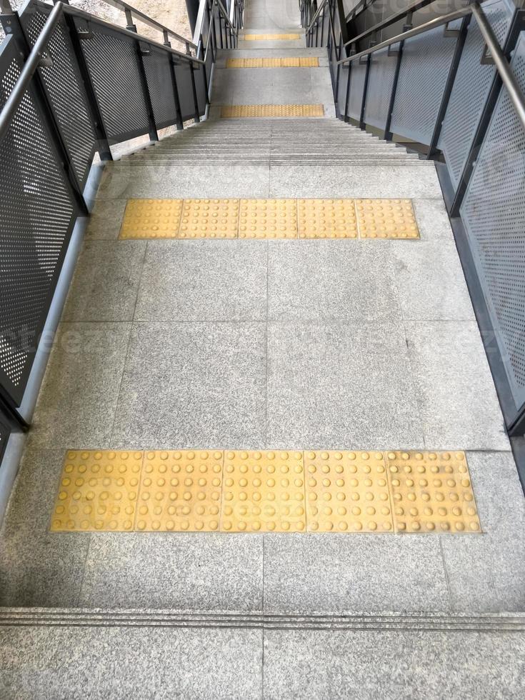 The braille block tile between the landing of the modern staircase for the visually impaired person. photo