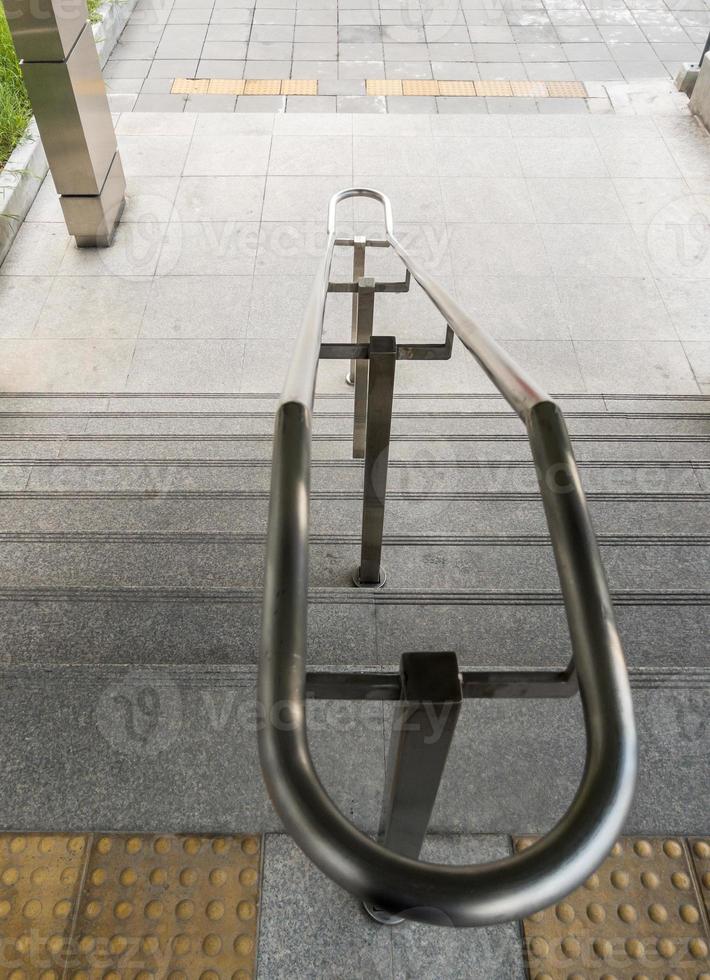 The stainless steel handrail on the staircase near the entrance of the urban railway station. photo