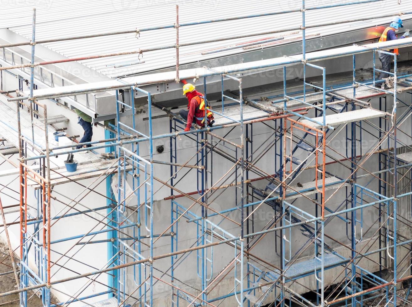 el trabajador de la construcción está trabajando en el andamio alto. foto