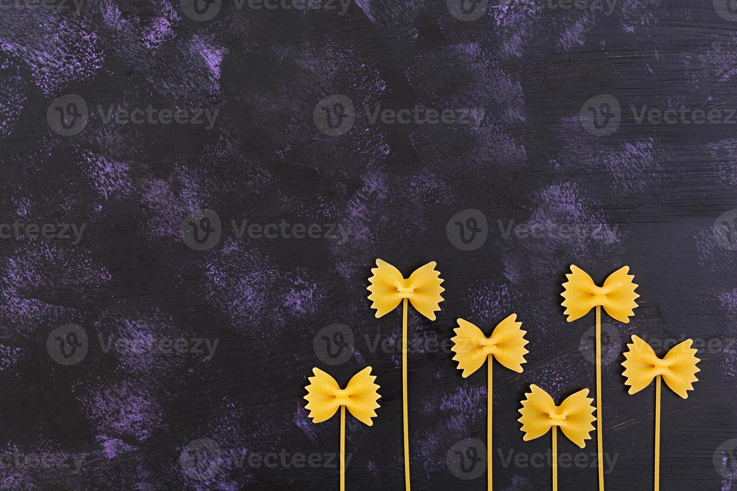 Dry pasta background. Close the raw farfalle pasta on dark background. Flat pattern. Top view. photo